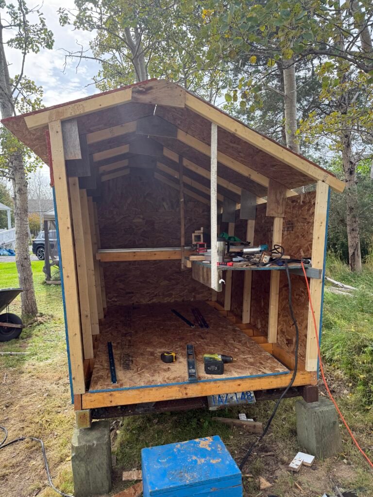 Front view through the open doorway of the Cove workshop, showing its unfinished interior and plywood frame.